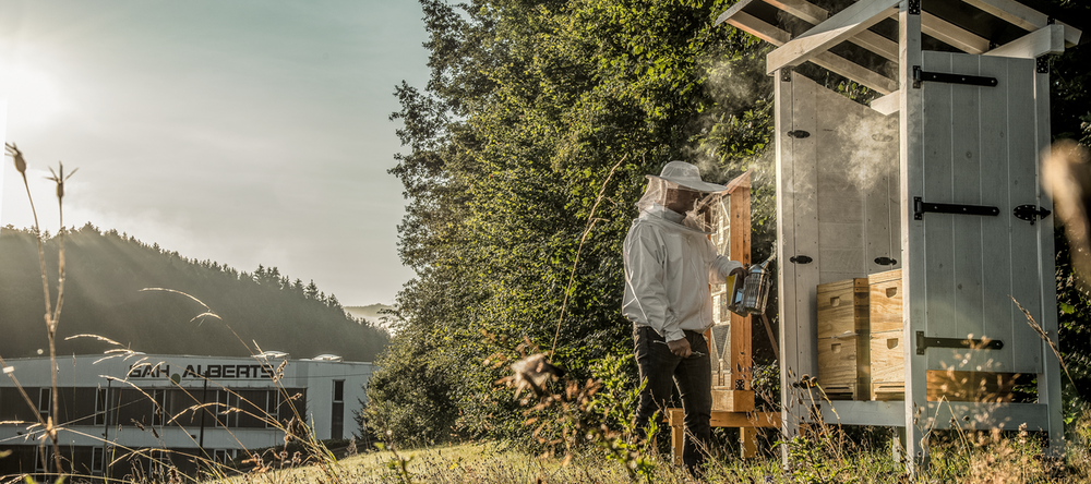 Ein Mitarbeiter von GAH Alberts versorgt den Bienenstock auf dem Betriebsgelände.